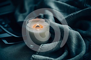 Burning candle in glass with wooden wick, handmade natural wax candle with knitted blanket