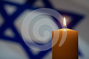 Burning candle on Israel flag background.