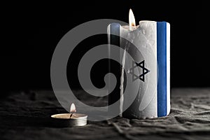 Burning candle with Israel flag on black background. War concept.