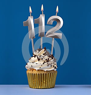 Burning candle number 112 - Birthday card with cake on blue Background