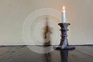 Burning candle in old candlestick