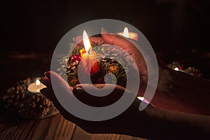 Burning candle on the palms of an elderly woman