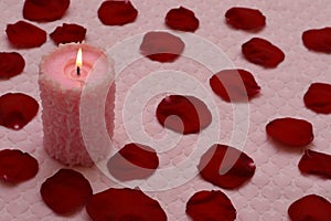 Burning candle and red rose petals photo