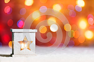 Burning candle, in snow, with defocussed fairy lights, boke in the background, Festive Christmas background