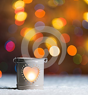 Burning candle, in snow, with defocussed fairy lights, boke in the background, Festive Christmas background