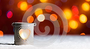 Burning candle, in snow, with defocussed fairy lights, bokeh in the background, Festive Christmas background