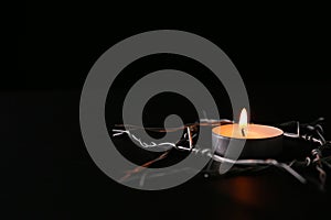 Burning candle and star of David made with barbed wire on black background, space for text. Holocaust memory day