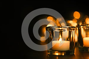 Burning candle on table in darkness. Funeral symbol