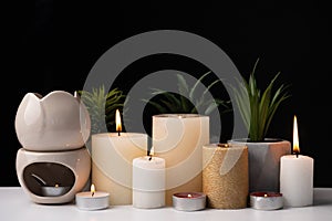 Burning candles and an aroma lamp on a black background. Incense, background for meditation and yoga.