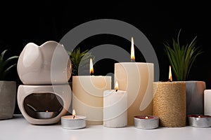 Burning candles and an aroma lamp on a black background. Incense, background for meditation and yoga.