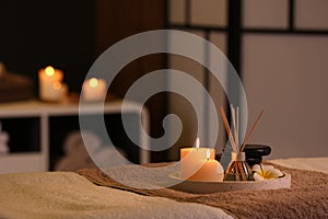 Burning candles and aromatic reed freshener on table in spa salon