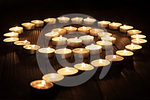 Burning candles arranged in spiral, circle at night on wooden table. Meditation, spiritual concept.