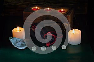 Burning candles, a bag with runes and a formula of the symbols Fehu, Mannaz,  Tiwaz and Wunjo