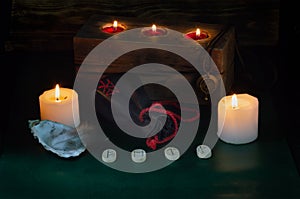 Burning candles, a bag with runes and a formula of the symbols Fehu, Mannaz,  Tiwaz and Wunjo photo