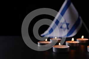 Burning candles on black table, space for text. Holocaust memory day