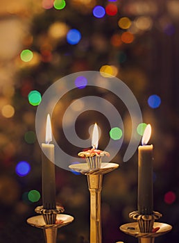 Burning candles on blurring Christmas lights background