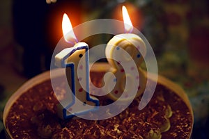 Burning candles on a cake in the form of the number eighteen, coming of age, blurred image