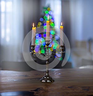 Burning candles in candelabra with bright bokeh on a black background