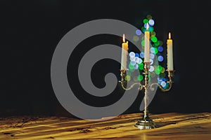 Burning candles in candelabra with bright bokeh on a black background