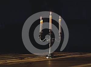 Burning candles in candelabra with bright bokeh on a black background