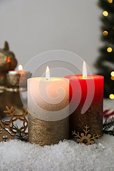 Burning candles and Christmas decor on artificial snow