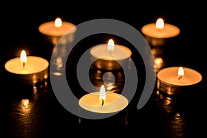 Burning candles on dark table, black background, Memory day.