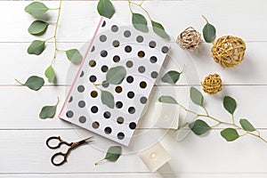 Burning candles with eucalyptus branches and notebook on white wooden background