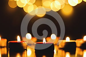 Burning candles with festive bokeh on a black background. Holiday concept. The concept of prayer, hope.