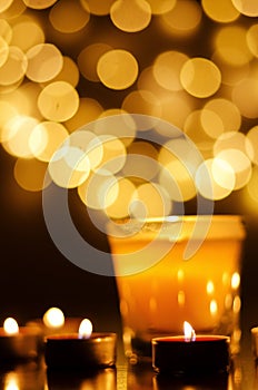 Burning candles with festive bokeh on a black background. Holiday concept. The concept of prayer, hope.