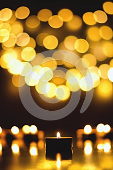 Burning candles with festive bokeh on a black background. Holiday concept. The concept of prayer, hope.