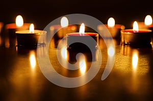 Burning candles with festive bokeh on a black background. Holiday concept. The concept of prayer, hope.