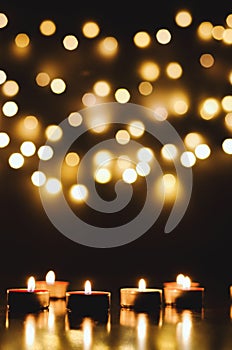 Burning candles with festive bokeh on a black background. Holiday concept. The concept of prayer, hope.