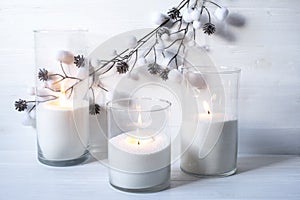 Burning candles with festive bokeh and silver balls on a light background.