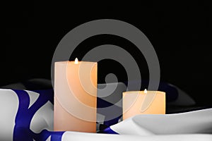 Burning candles and flag of Israel on dark background. Holocaust remembrance day