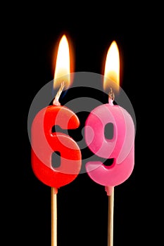 Burning candles in the form of 69 sixty nine numbers, dates for cake isolated on black background. The concept of celebrating a