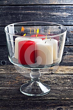 Burning candles in a glass vase on a wooden background