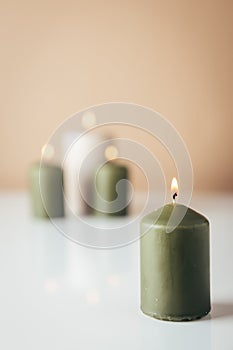 Burning candles in green and beige colors