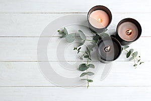 Burning candles and green branches on white wooden table, flat lay.