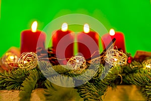 Burning candles for X-Mas on a advents wreath with a neutral green background.