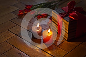 Burning candles, open gift box present, red tulips on wooden background. Romance.