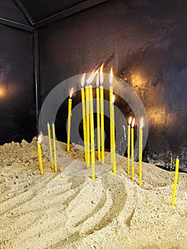 Burning candles in orthodox church. Burning candles shining in dark background. Copy space.