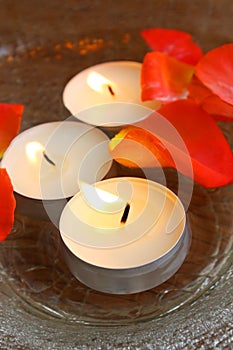 Burning candles and petals in bowl