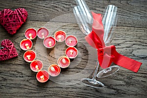 Burning candles in the shape of heart with two flutes