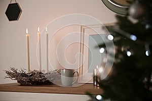 Burning candles on shelf near Christmas tree