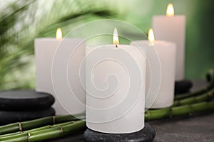 Burning candles, spa stones and bamboo sprouts on grey table against blurred