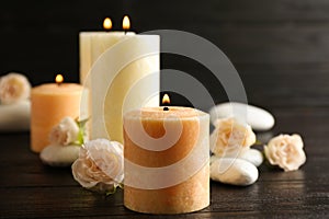 Burning candles, spa stones and flowers on table.