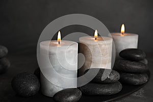 Burning candles and spa stones on  plate, closeup