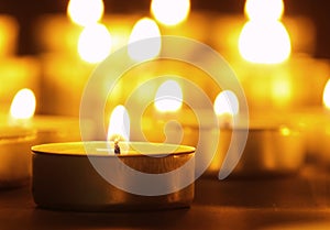 Burning candles with a yellow flame on a black table with a blurred background. Christmas candles. Lighted candles at night in the