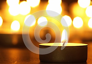 Burning candles with a yellow flame on a black table with a blurred background. Christmas candles. Lighted candles at night in the