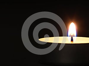 Burning candles with a yellow flame on a black table with a blurred background. Christmas candles. Lighted candles at night in the